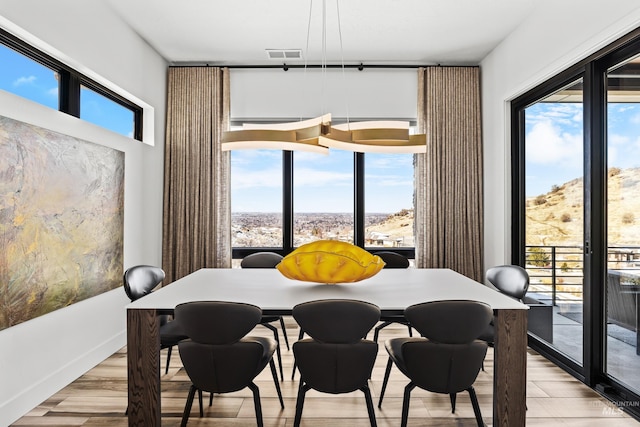 dining space featuring light wood-style floors, plenty of natural light, and visible vents