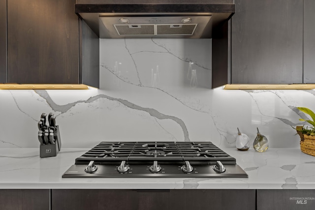 kitchen featuring backsplash, exhaust hood, dark brown cabinetry, and stainless steel gas stovetop