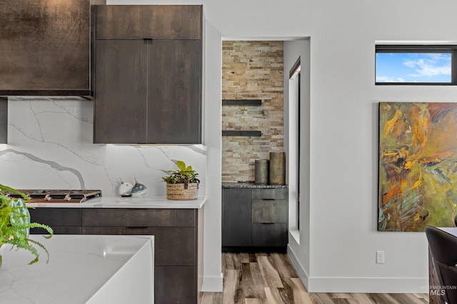 kitchen with light wood finished floors, modern cabinets, backsplash, and dark brown cabinets