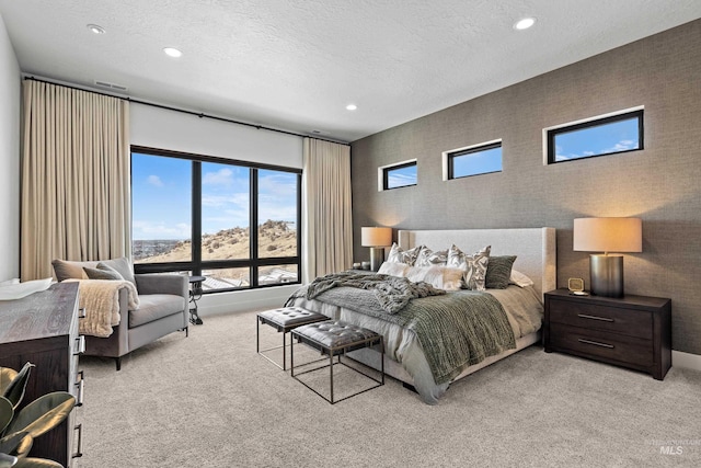 bedroom featuring light carpet, a textured ceiling, and recessed lighting