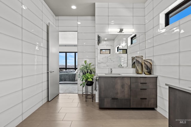 bathroom featuring ensuite bathroom, tile walls, and vanity