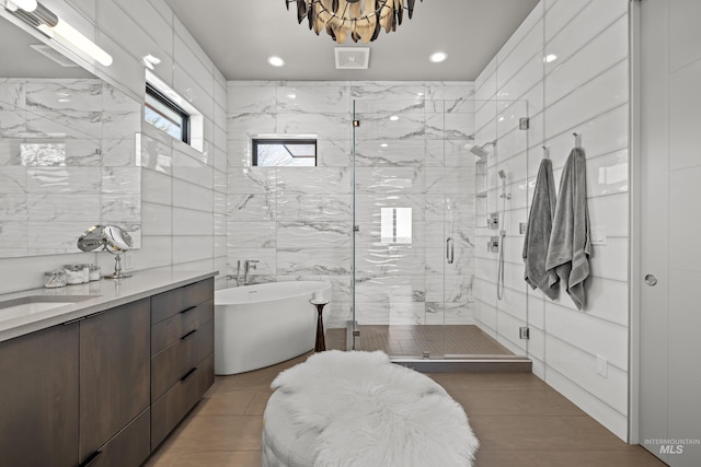 full bath featuring tile walls, a soaking tub, visible vents, a stall shower, and vanity