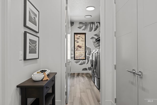 laundry area with a textured ceiling, laundry area, light wood-type flooring, and washing machine and dryer