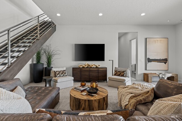 living area with recessed lighting, carpet flooring, a textured ceiling, and stairs