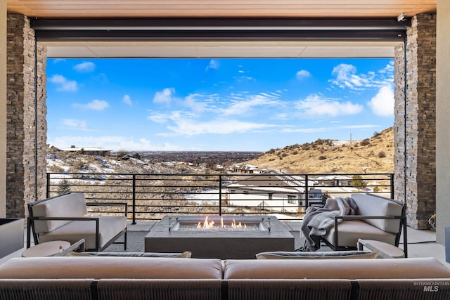 view of patio featuring a balcony and an outdoor living space with a fire pit