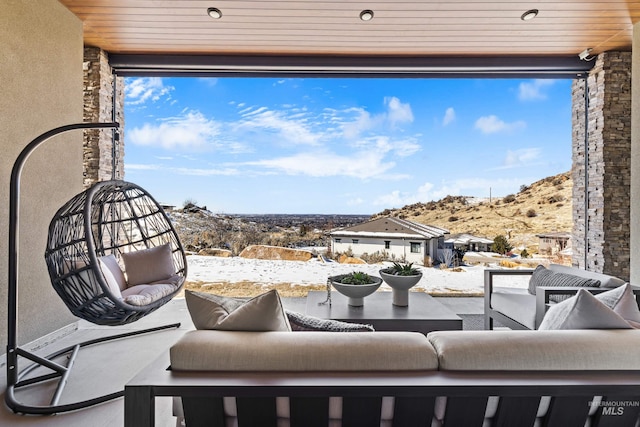 snow covered patio with a mountain view and outdoor lounge area