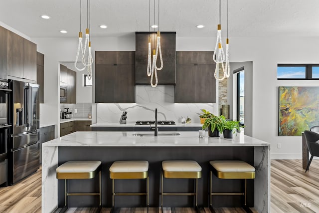 kitchen featuring an island with sink, modern cabinets, appliances with stainless steel finishes, and decorative backsplash