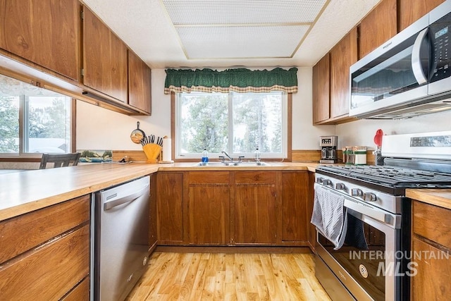 kitchen featuring brown cabinetry, stainless steel appliances, light countertops, and a sink