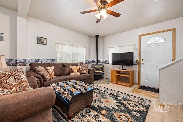 living room featuring a wood stove and a ceiling fan