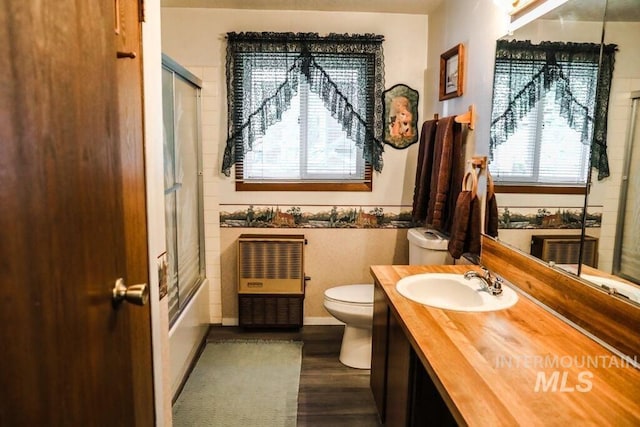 bathroom with plenty of natural light, toilet, vanity, and wood finished floors