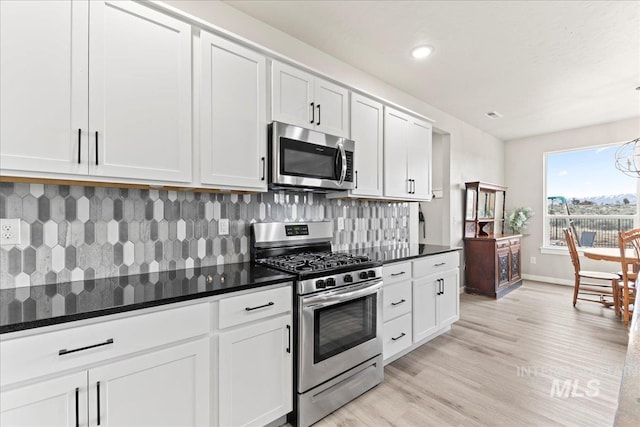 kitchen featuring decorative backsplash, light wood-style flooring, white cabinets, and appliances with stainless steel finishes