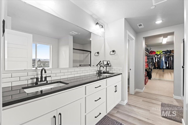 bathroom featuring visible vents, a stall shower, wood finished floors, and a sink