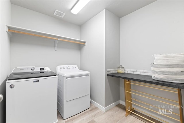 laundry room with visible vents, separate washer and dryer, light wood finished floors, baseboards, and laundry area