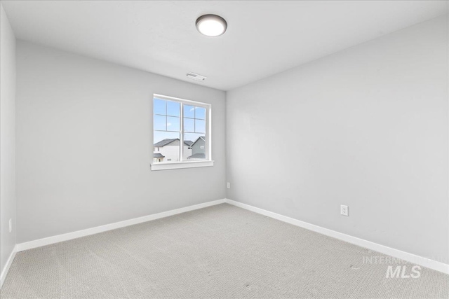 carpeted spare room featuring baseboards and visible vents