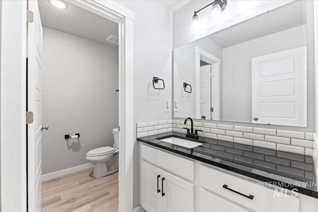 bathroom with vanity, toilet, wood finished floors, and baseboards