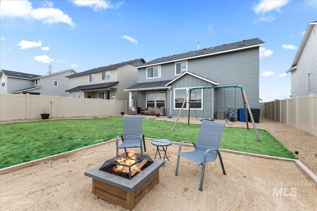 rear view of house with a patio, an outdoor fire pit, a fenced backyard, central AC, and a lawn