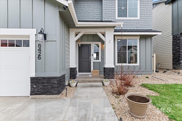 view of exterior entry with board and batten siding and a garage