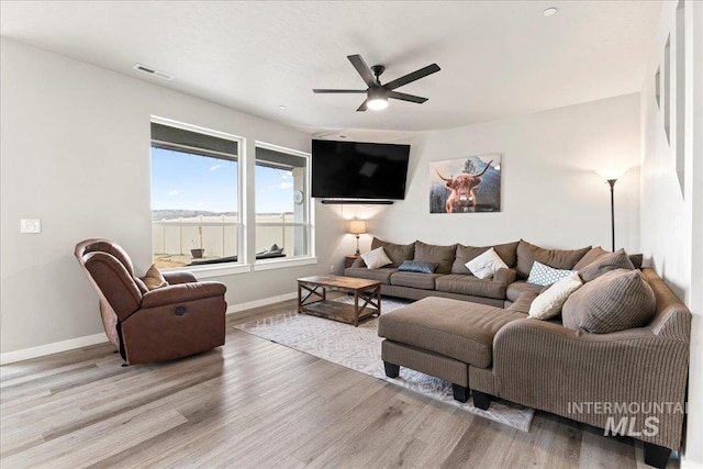 living room with visible vents, baseboards, wood finished floors, and a ceiling fan