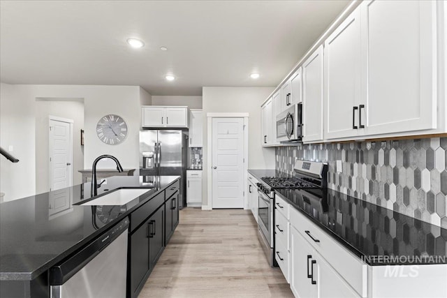 kitchen with decorative backsplash, stainless steel appliances, an island with sink, and a sink