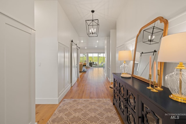 1305 N Big Star Pl, Eagle, ID 83616 - hallway featuring a barn door, light wood-style flooring, and a chandelier