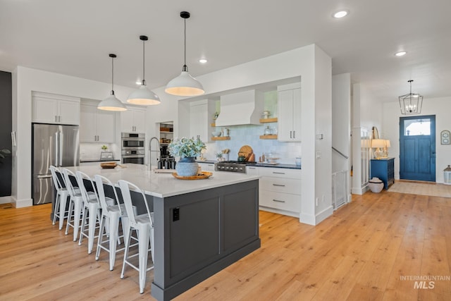 1305 N Big Star Pl, Eagle, ID 83616 - kitchen featuring stainless steel appliances, premium range hood, white cabinetry, light wood finished floors, and decorative backsplash