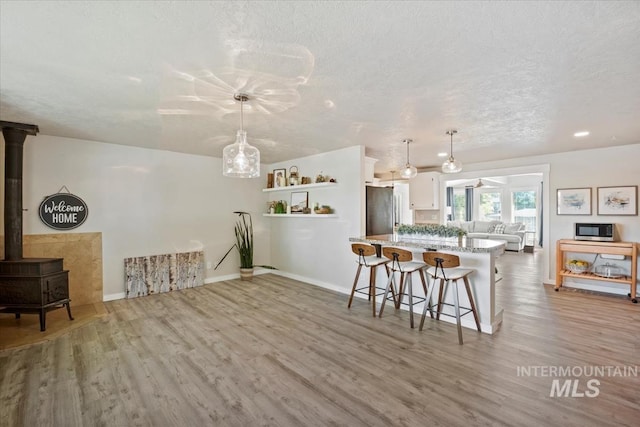 632 N Edgewood Ln, Eagle, ID 83616 - kitchen featuring light wood-type flooring, a kitchen breakfast bar, white cabinets, appliances with stainless steel finishes, and a textured ceiling