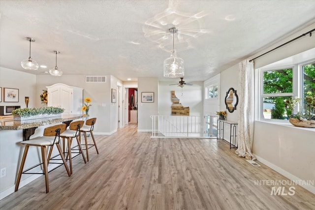 632 N Edgewood Ln, Eagle, ID 83616 - kitchen featuring stainless steel microwave, light wood finished floors, a breakfast bar, white cabinets, and decorative light fixtures