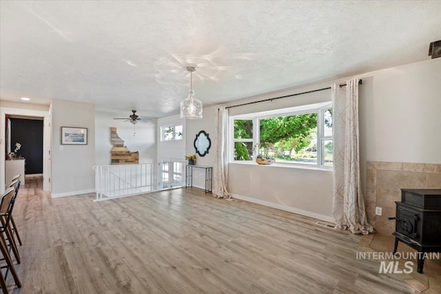632 N Edgewood Ln, Eagle, ID 83616 - unfurnished living room featuring a wood stove, wood finished floors, a textured ceiling, and a ceiling fan
