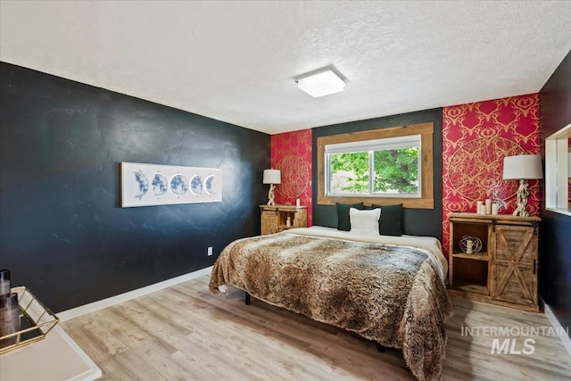 632 N Edgewood Ln, Eagle, ID 83616 - bedroom featuring an accent wall, wood finished floors, wallpapered walls, and a textured ceiling