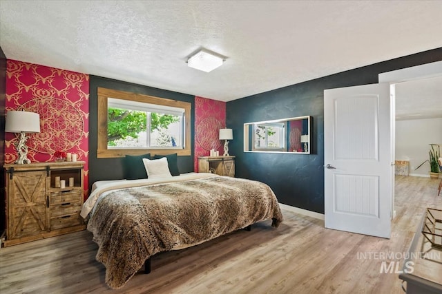 632 N Edgewood Ln, Eagle, ID 83616 - bedroom featuring a textured ceiling, wood finished floors, wallpapered walls, and an accent wall