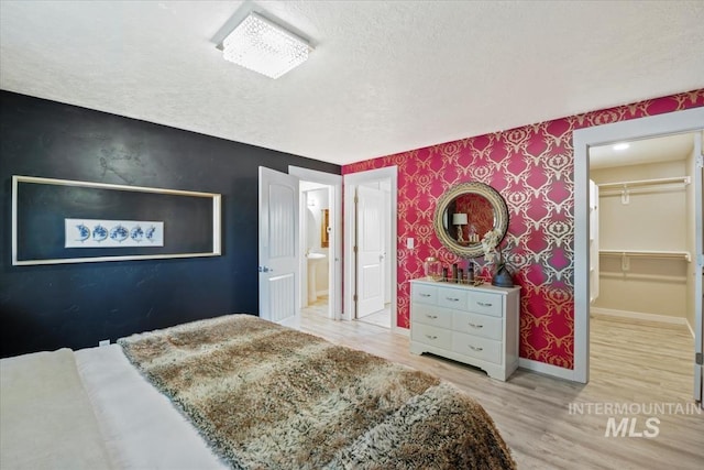 632 N Edgewood Ln, Eagle, ID 83616 - bedroom with a textured ceiling, wallpapered walls, wood finished floors, a spacious closet, and an accent wall