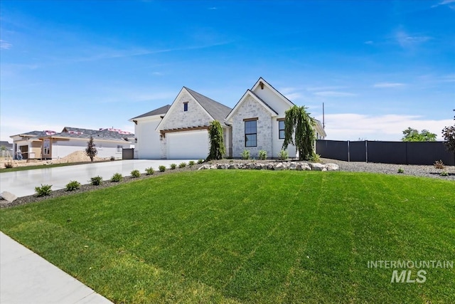 view of front facade with driveway, stone siding, a front yard, and fence