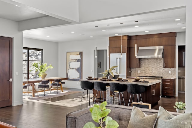 510 W Paso Fino Dr, Boise, ID 83702 - kitchen with a breakfast bar area, high end refrigerator, hanging light fixtures, a center island with sink, and wall chimney range hood