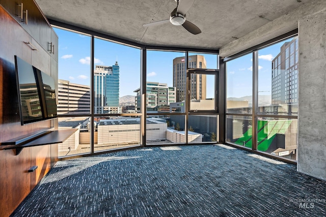 unfurnished sunroom with ceiling fan and a view of city