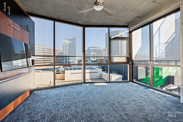 unfurnished sunroom featuring a ceiling fan and a view of city