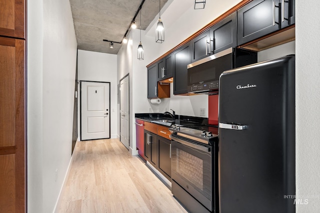 kitchen with light wood-style floors, dark countertops, black electric range, fridge, and a sink