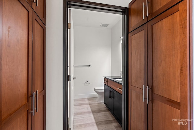 bathroom featuring toilet, wood finished floors, vanity, visible vents, and baseboards