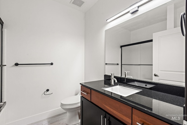 full bathroom featuring visible vents, toilet, a shower with door, wood finished floors, and vanity