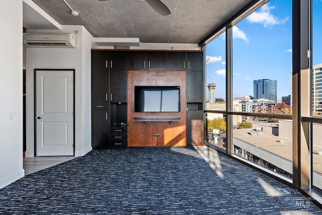 interior space with carpet floors, a ceiling fan, a wall of windows, a wall mounted air conditioner, and baseboards