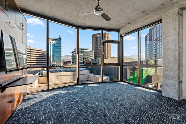 unfurnished sunroom with a ceiling fan and a city view