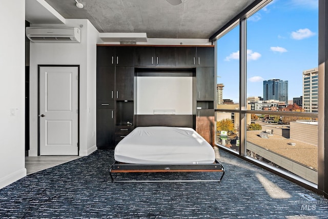 carpeted bedroom featuring baseboards, a closet, a wall mounted AC, a view of city, and a wall of windows