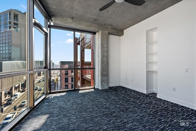 carpeted spare room featuring baseboards and a ceiling fan