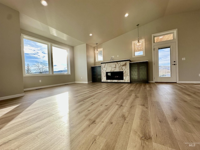 unfurnished living room with light hardwood / wood-style flooring, a fireplace, and vaulted ceiling