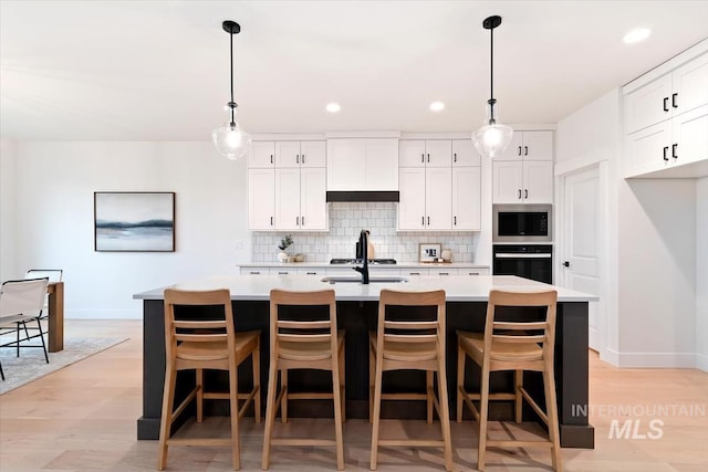 kitchen featuring light countertops, black oven, stainless steel microwave, and decorative backsplash