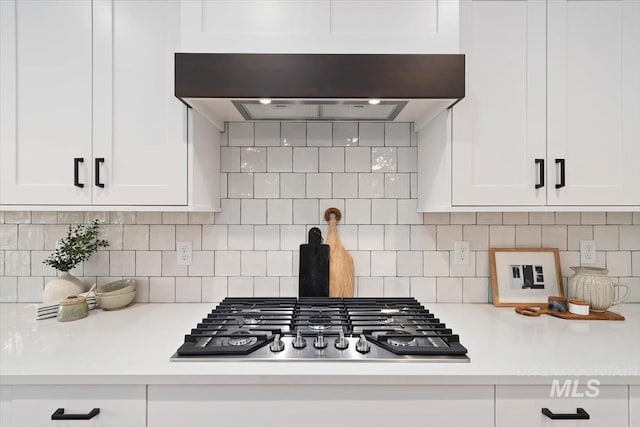 kitchen with light countertops, stainless steel gas stovetop, decorative backsplash, white cabinets, and premium range hood