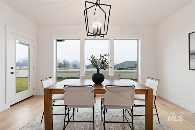 dining space with light wood-style floors, baseboards, and a chandelier