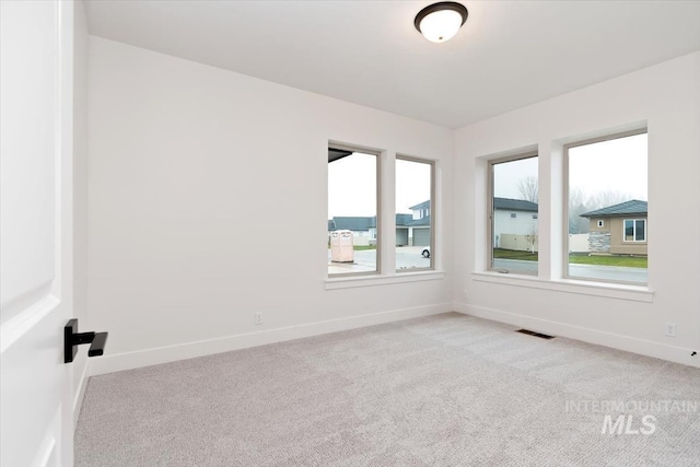 spare room with carpet, visible vents, plenty of natural light, and baseboards