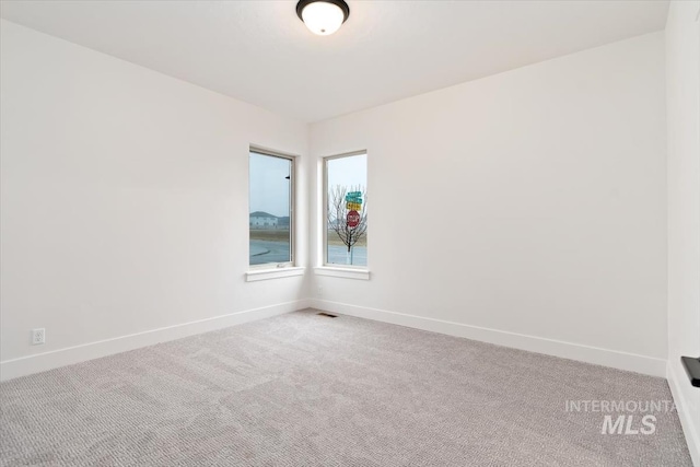 spare room featuring carpet flooring, visible vents, and baseboards