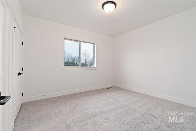 empty room with baseboards and light colored carpet