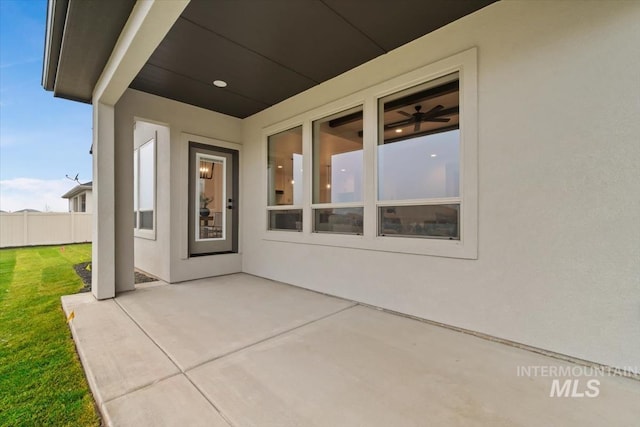 doorway to property with a yard, a patio area, fence, and stucco siding